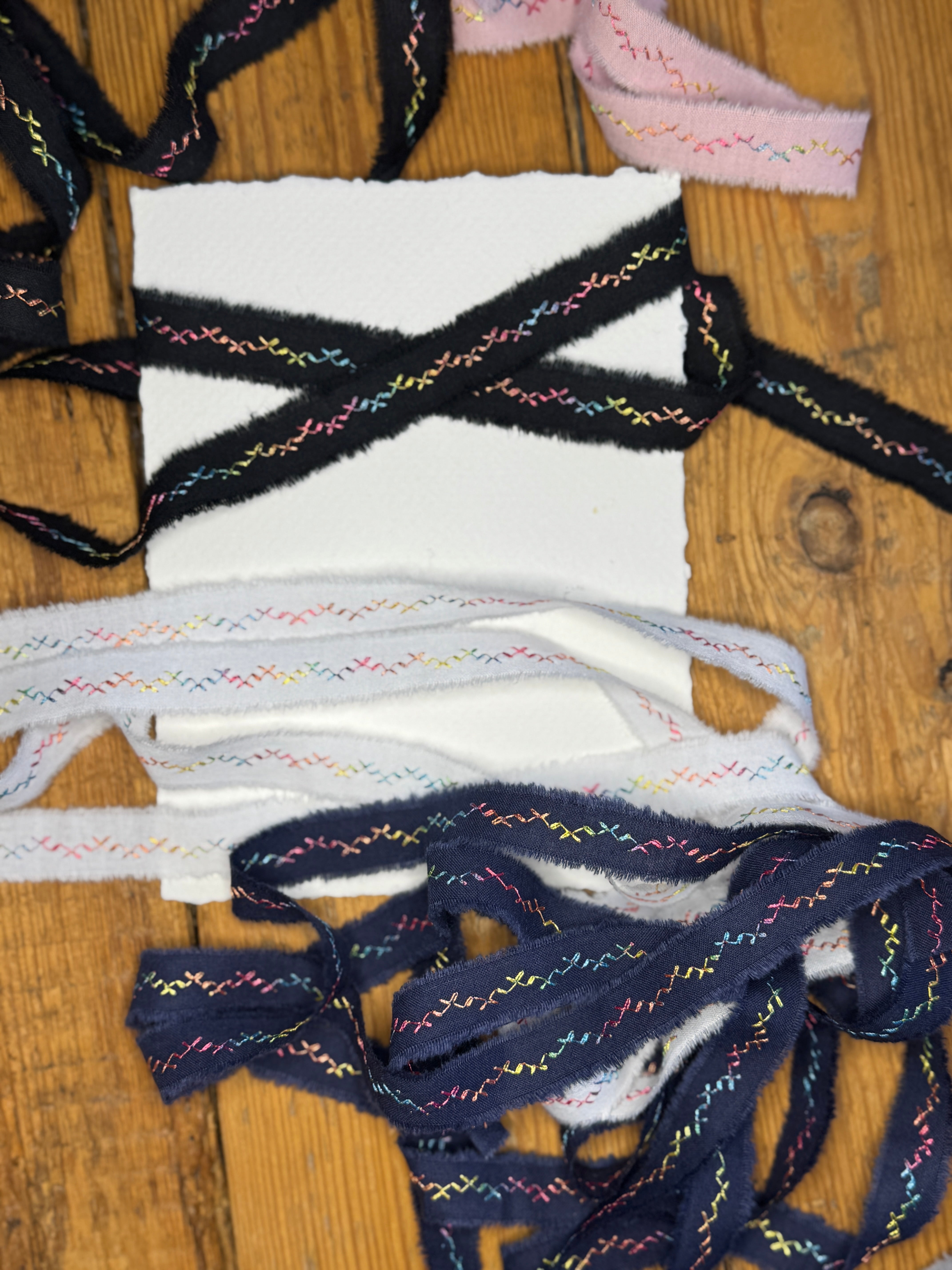 Colorful embroidered hand-torn cotton ribbon on a wooden surface